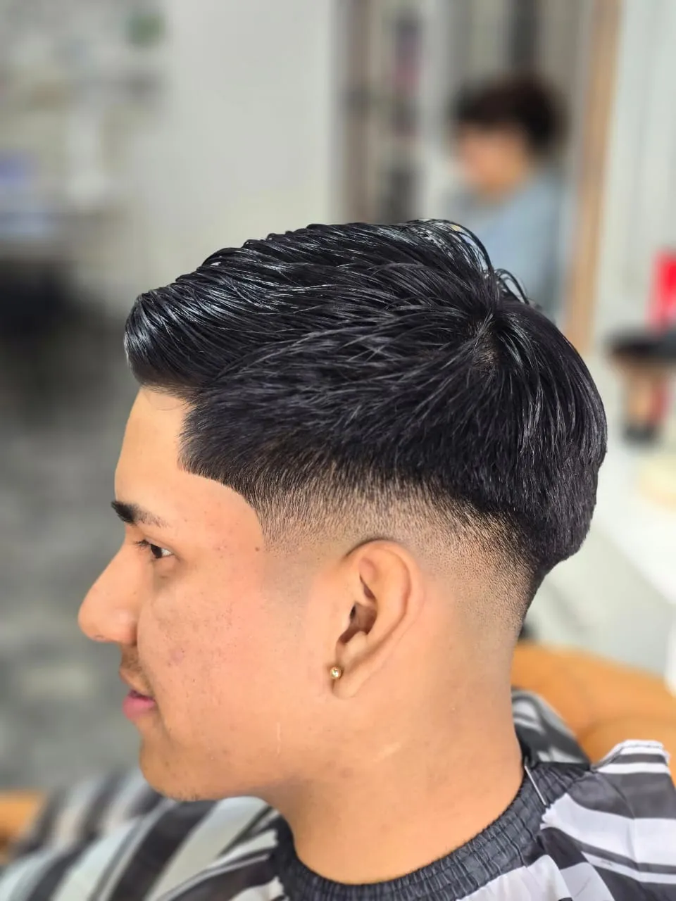 Cliente de perfil con un degradado bajo y el pelo peinado hacia un lado