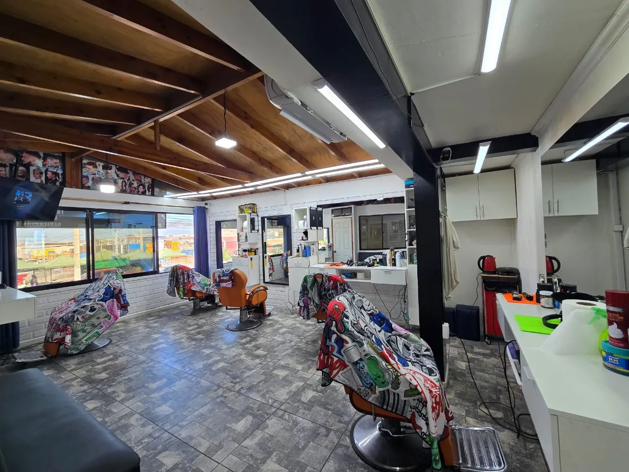 Vista general del salón, con techo de madera y sillones de barbero