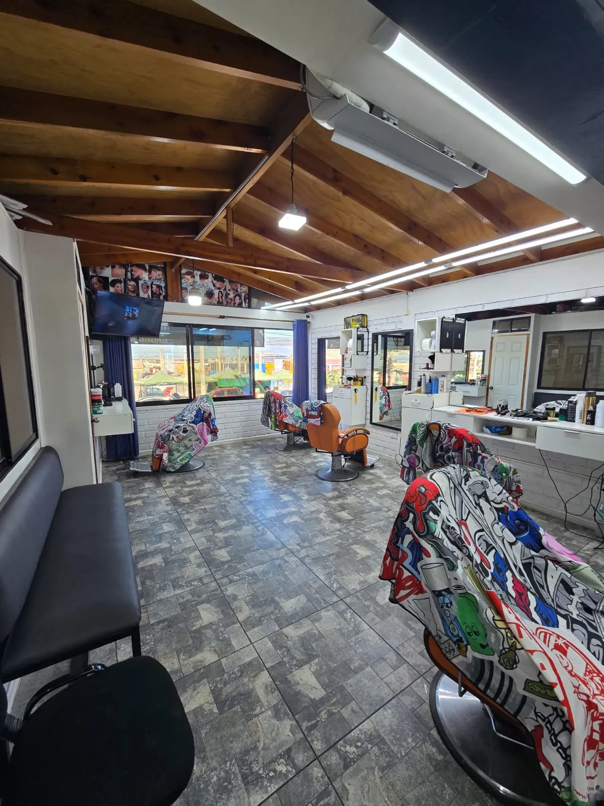 Interior del salón con sillones de barbero y ventanales